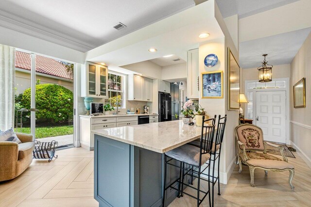 396 Kelsey Park Dr, Palm Beach Gardens, FL 33410 - kitchen with visible vents, light stone countertops, a breakfast bar area, a sink, and black appliances