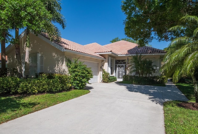 mediterranean / spanish-style house featuring a tile roof, concrete driveway, a garage, and stucco siding