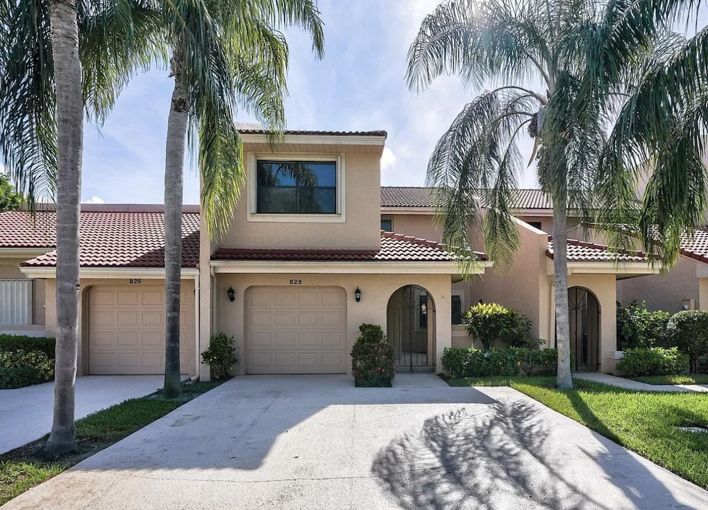 mediterranean / spanish home with stucco siding, a garage, driveway, and a tile roof