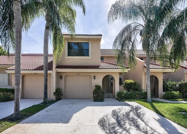 mediterranean / spanish home with stucco siding, a garage, driveway, and a tile roof