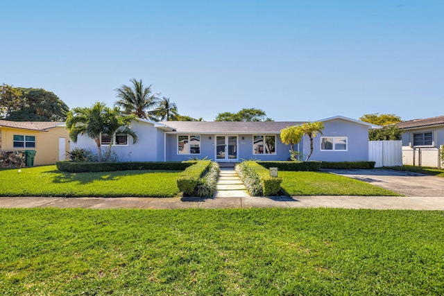 single story home with fence, driveway, stucco siding, a front lawn, and french doors