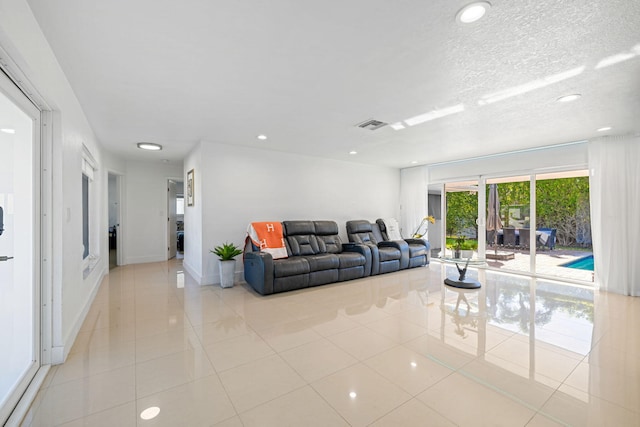 living area featuring visible vents, a textured ceiling, recessed lighting, light tile patterned floors, and baseboards