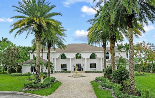 mediterranean / spanish-style house featuring stucco siding, curved driveway, and a front yard