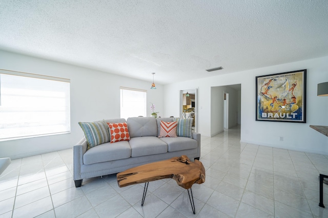 living room featuring light tile patterned floors, visible vents, and a textured ceiling