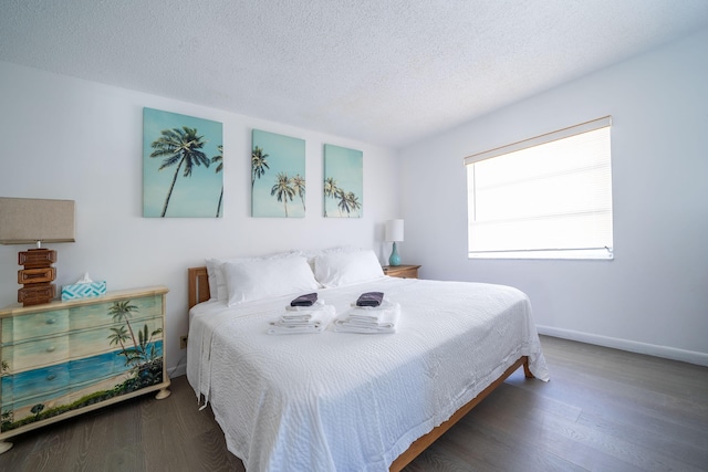 bedroom with a textured ceiling, baseboards, and wood finished floors