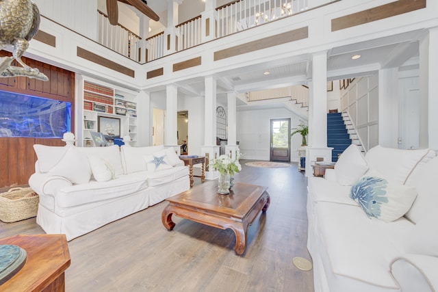 living room featuring stairway, built in features, wood finished floors, and ornate columns
