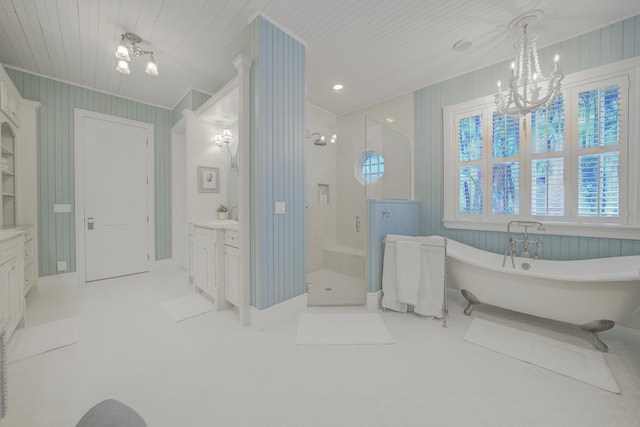 bathroom with a freestanding bath, a stall shower, baseboards, a notable chandelier, and vanity