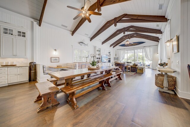 dining space featuring wood finished floors, visible vents, lofted ceiling with beams, and ceiling fan
