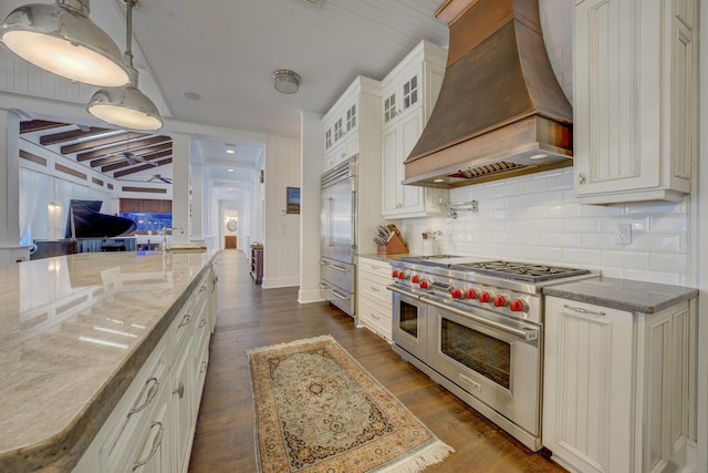 kitchen featuring custom exhaust hood, high end appliances, decorative backsplash, glass insert cabinets, and light stone counters