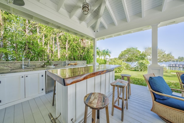 wooden terrace featuring outdoor wet bar, an outdoor kitchen, and ceiling fan
