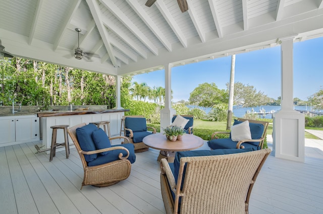 wooden terrace featuring outdoor dry bar, an outdoor hangout area, a water view, and ceiling fan