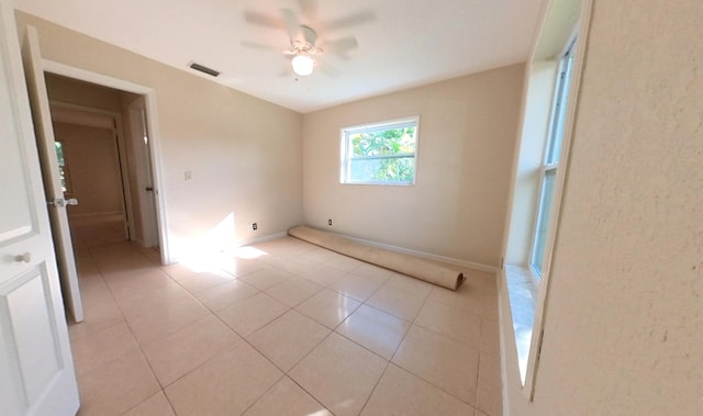 unfurnished room featuring light tile patterned flooring, visible vents, baseboards, and a ceiling fan