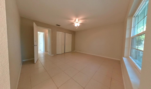 unfurnished bedroom with light tile patterned floors, baseboards, visible vents, and ceiling fan