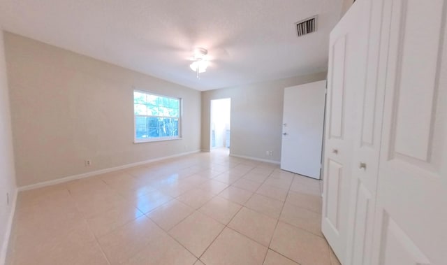 unfurnished room with light tile patterned floors, visible vents, and baseboards