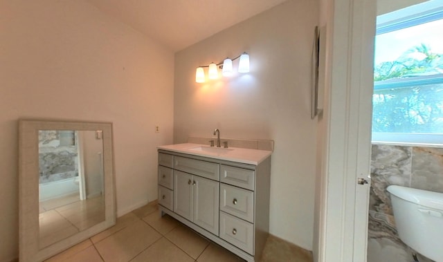 bathroom with tile patterned flooring, toilet, vanity, and vaulted ceiling