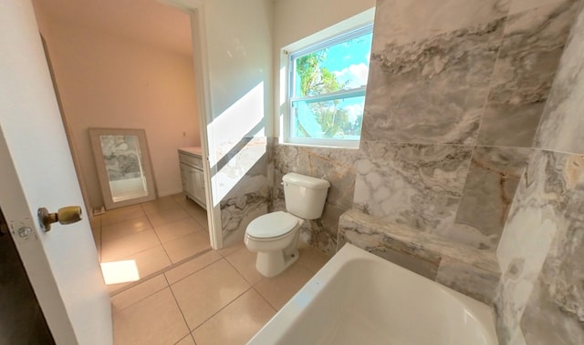 full bathroom featuring tile patterned flooring, a tub, tile walls, toilet, and vanity