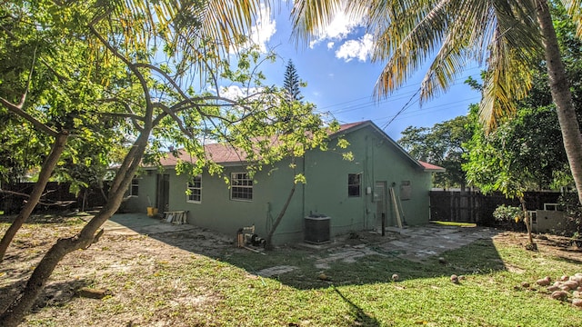 rear view of property with stucco siding, a patio area, central AC, and fence