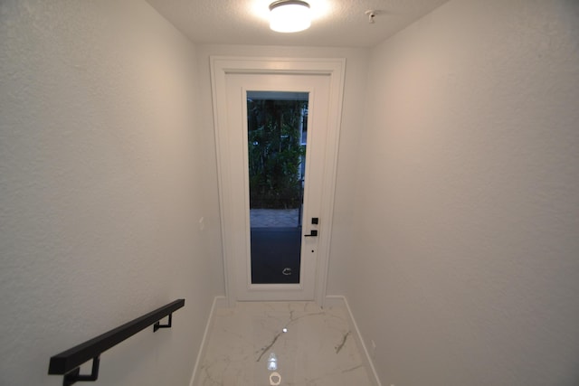 entryway featuring marble finish floor, a textured ceiling, and baseboards