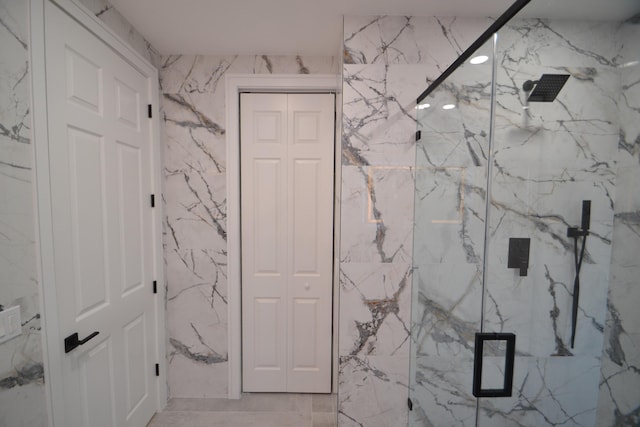 full bath featuring stone wall, a marble finish shower, and a closet