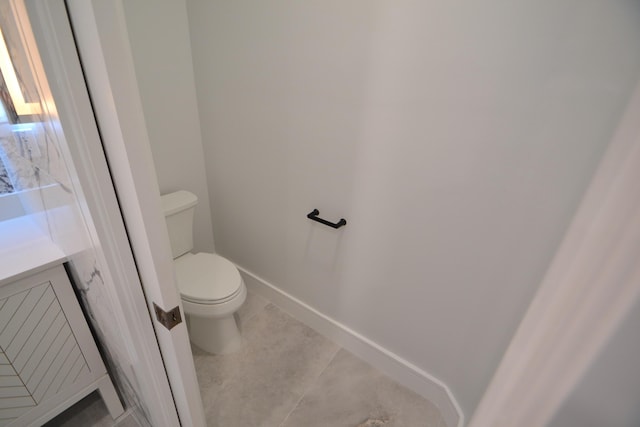 bathroom featuring baseboards, toilet, vanity, and tile patterned flooring