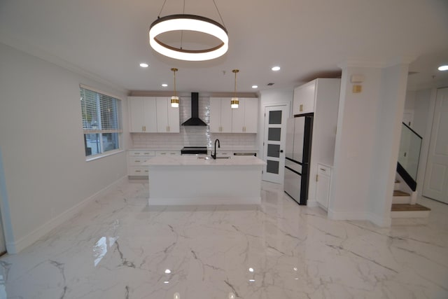 kitchen featuring backsplash, crown molding, light countertops, freestanding refrigerator, and wall chimney exhaust hood