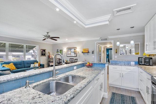 kitchen featuring wood finish floors, visible vents, white cabinets, and a sink