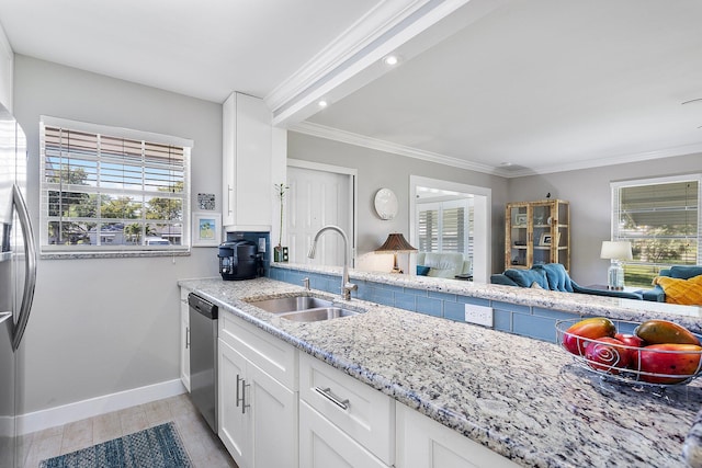 kitchen featuring appliances with stainless steel finishes, light stone countertops, crown molding, and a sink