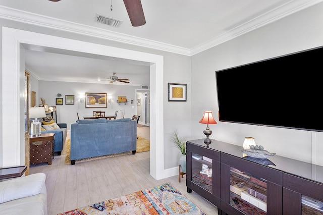 living area featuring baseboards, visible vents, ornamental molding, ceiling fan, and light wood-style floors