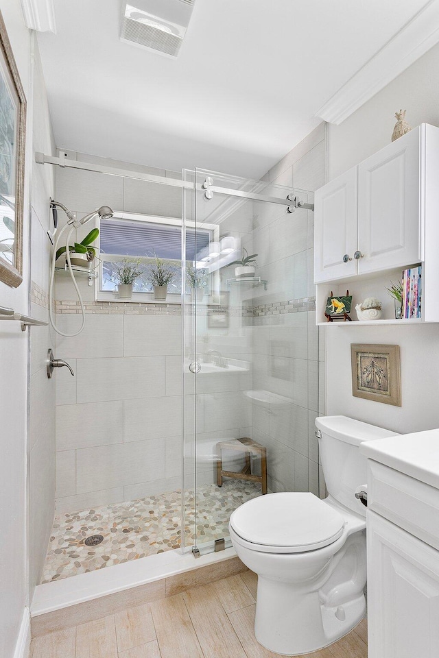 full bathroom with visible vents, a stall shower, toilet, and vanity