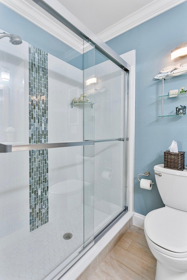 bathroom featuring toilet, a stall shower, and crown molding