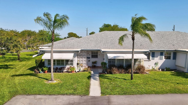 ranch-style home with stucco siding, a front lawn, and a shingled roof