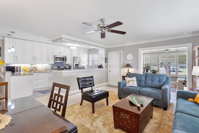 living room with a healthy amount of sunlight, baseboards, crown molding, and ceiling fan