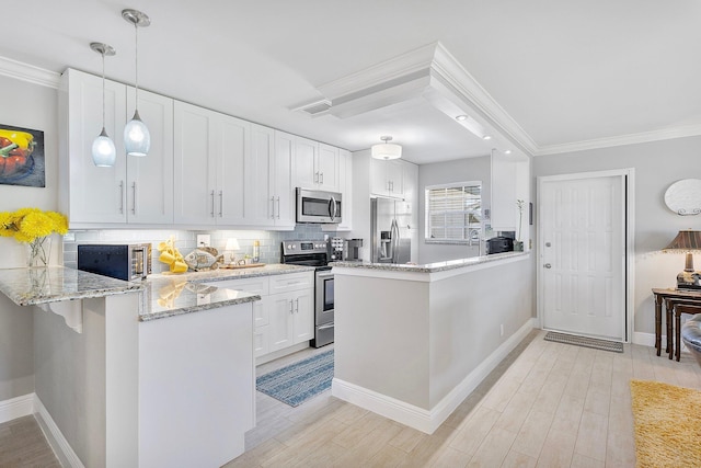 kitchen with a peninsula, stainless steel appliances, decorative backsplash, white cabinets, and light wood-type flooring