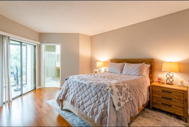 bedroom with ensuite bath, a textured ceiling, light wood-type flooring, and access to outside