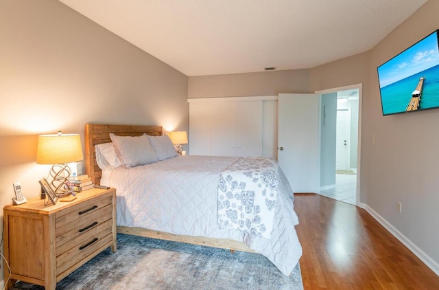 bedroom with a closet, baseboards, visible vents, and wood finished floors