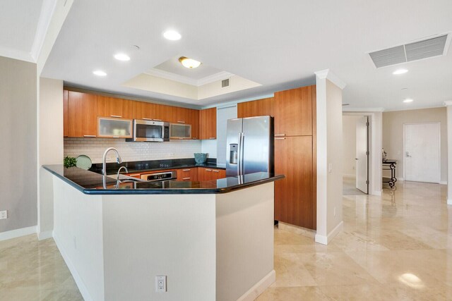 2650 Lake Shore Dr Unit 703, Riviera Beach, FL 33404 - kitchen with visible vents, a peninsula, brown cabinets, a tray ceiling, and stainless steel appliances
