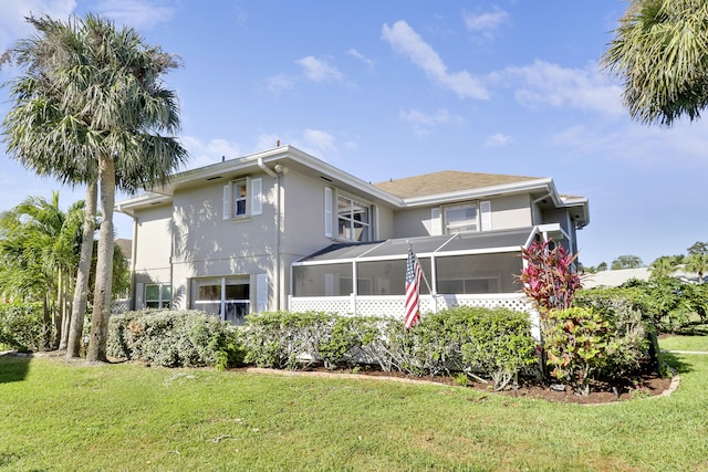 back of property featuring a yard, a sunroom, and stucco siding