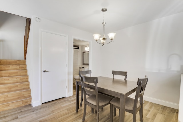 dining space with an inviting chandelier, stairway, light wood-style floors, and baseboards