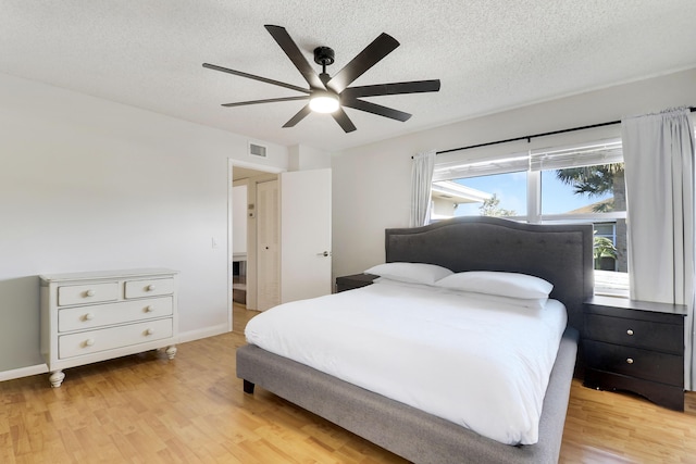 bedroom with visible vents, light wood-style floors, a ceiling fan, and a textured ceiling