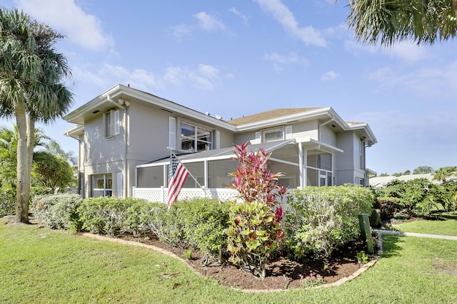 view of home's exterior with stucco siding, a yard, and a sunroom