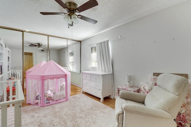 bedroom featuring ceiling fan, wood finished floors, and a textured ceiling