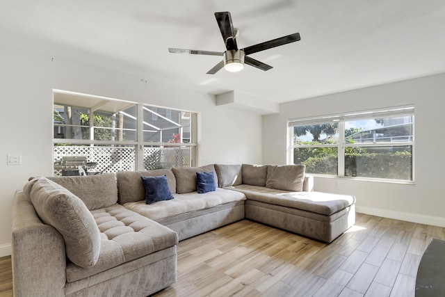 living area featuring baseboards, light wood-type flooring, and ceiling fan