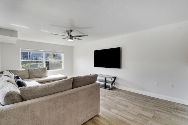 living area with baseboards, a ceiling fan, and light wood-style floors