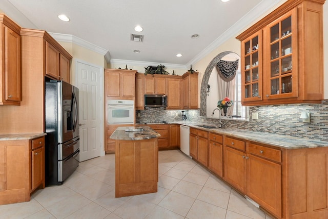 kitchen featuring visible vents, a sink, a center island, white appliances, and glass insert cabinets