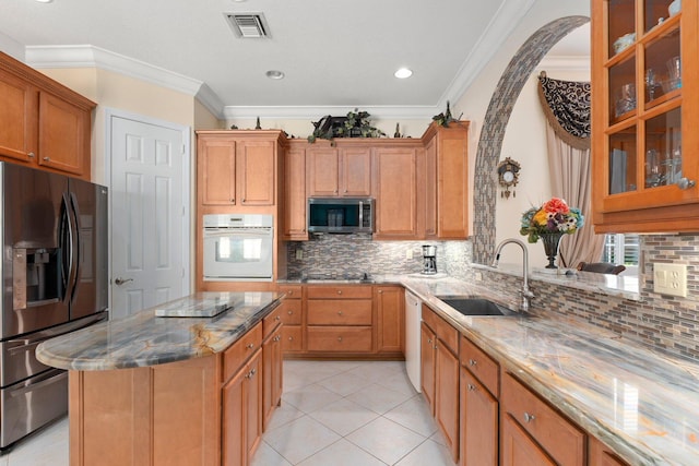 kitchen featuring tasteful backsplash, visible vents, light stone counters, stainless steel appliances, and a sink