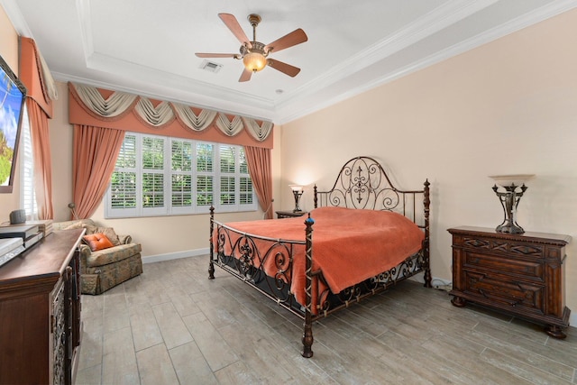 bedroom with visible vents, ornamental molding, a tray ceiling, wood finished floors, and baseboards