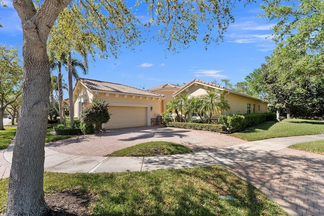 view of front facade with a front yard, decorative driveway, a garage, and stucco siding