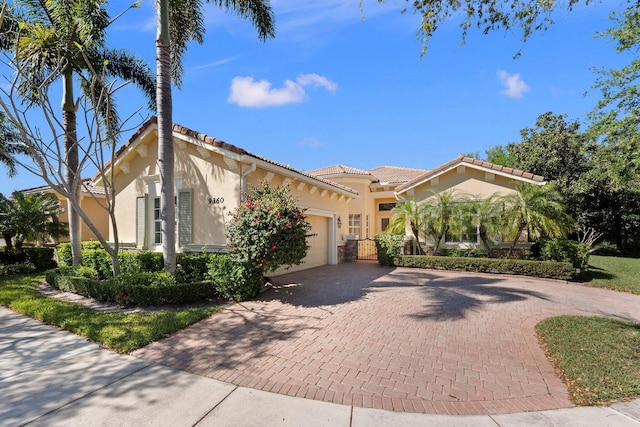 mediterranean / spanish home featuring decorative driveway, a tile roof, an attached garage, and stucco siding