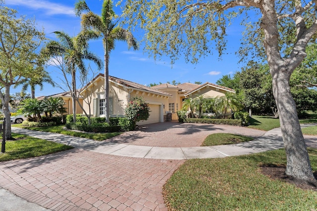 view of front of property featuring stucco siding, decorative driveway, a front yard, a garage, and a tiled roof