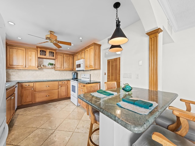 kitchen featuring a breakfast bar, ornate columns, tasteful backsplash, white appliances, and hanging light fixtures